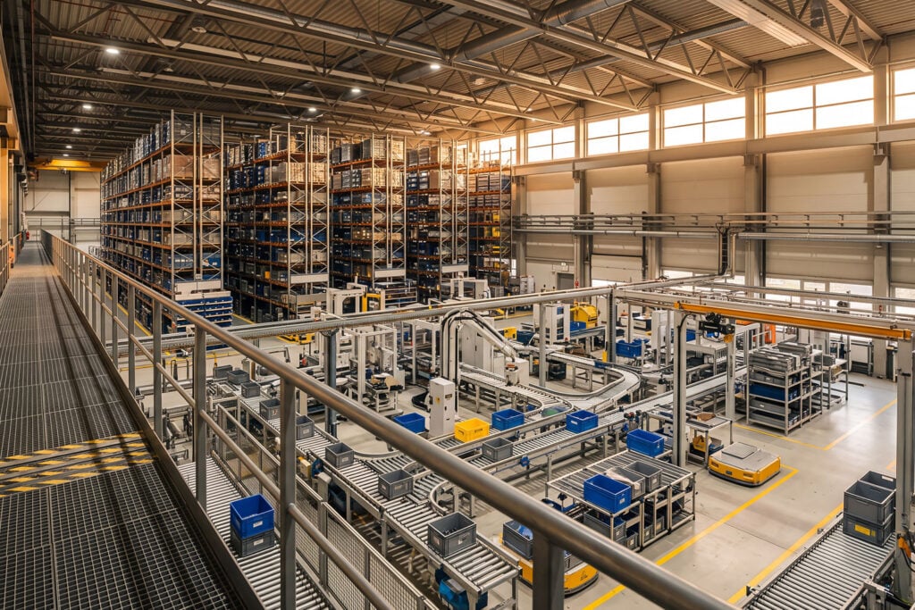 Modern automated warehouse with robotic assembly line high-density storage racks and conveyor system in a large industrial factory facility